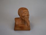 une petite statue représentant un homme barbu posée sur une surface blanche