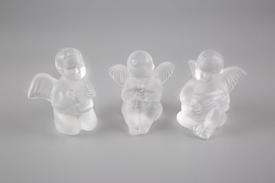 trois figurines blanches représentant des anges, posées sur une surface blanche