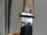 someone is holding a knife in their right hand and a pair of scissors in the background
