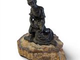 statue représentant un homme agenouillé sur un rocher avec un chien