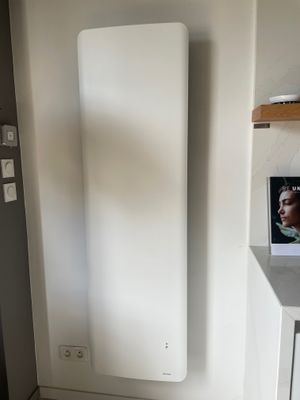 un radiateur dans un coin d'une pièce où est accroché un tableau au mur