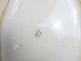 a close up of a white porcelain vase with a brown spot on it