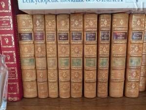 de nombreux livres anciens sur une étagère, à côté d'un verre d'eau