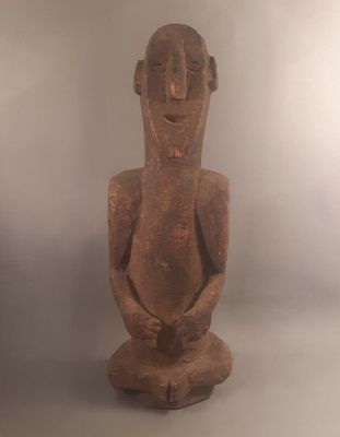 une vieille statue en bois représentant un homme assis sur une surface blanche