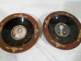 deux assiettes noires et dorées sur lesquelles figurent les portraits d'un homme et d'une femme