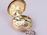 a small gold pocket watch with a key in it