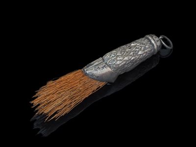 un gros plan d'un pinceau argenté et marron sur une surface noire