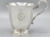 a silver cup with a handle on a pedestal