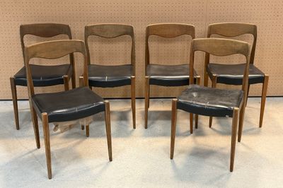 quatre chaises aux assises en cuir noir devant un mur beige