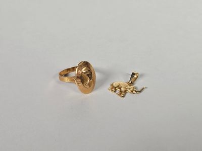 une bague en or et un pendentif en forme d'éléphant en or sur un fond blanc