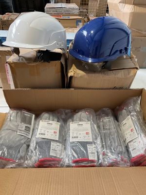 Des cartons contenant des casques de chantier sont empilés les uns sur les autres dans un entrepôt