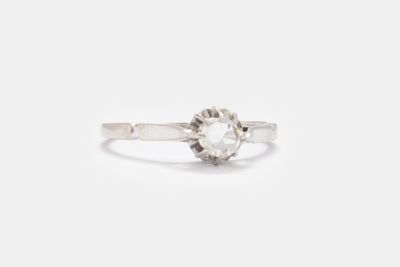 un gros plan d'une bague sertie d'un diamant blanc sur une surface blanche