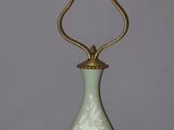 a green vase with a gold base on a table