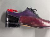 purple and black dress shoes hanging on a wall with a red tie