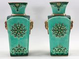 paire de vases verts avec des anses dorées sur fond blanc