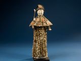 statue of a woman in a fur coat and hat holding a stick
