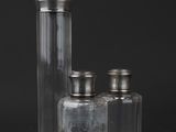 three glass jars with silver lids on a black surface