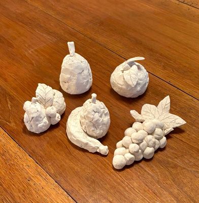 five figurines of fruit on a wooden table
