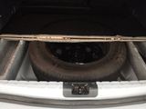 the trunk of a white car with a flat tire in the trunk