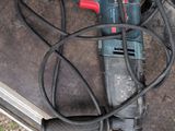 une perceuse posée par terre à côté de quelques fils électriques