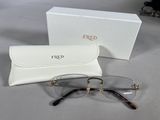 une paire de lunettes et son étui posés sur une table à côté d'une boîte blanche