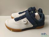 Les chaussures sont blanches et bleues, avec une semelle marron.