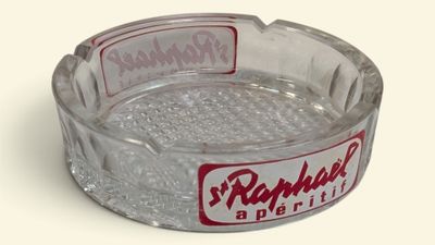 un cendrier en verre orné d'un logo rouge et blanc
