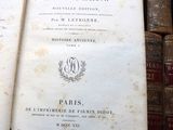 an old book on a table with many books in the background