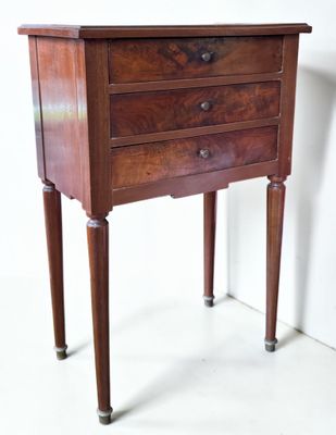 a small wooden table with three drawers on it