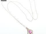 a close up of a necklace with a pink stone on a chain