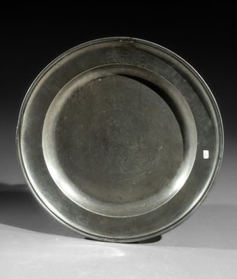 an old silver plate sitting on top of a white table