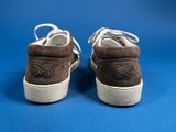 brown sued sneakers with white soles on a blue background