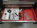 a red drawer with tools in it and a pair of scissors in it