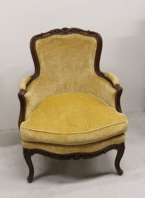 une vieille chaise avec un coussin rembourré jaune et une structure en bois