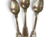 three silver spoons sitting next to each other on a white surface