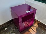 une table violette avec un plateau en verre, placée devant une fenêtre