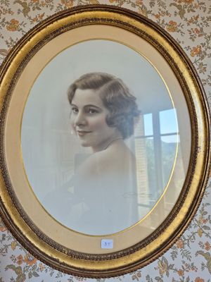 Une vieille photo représentant une femme en robe blanche est accrochée au mur.