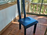 une chaise bleue posée sur un sol carrelé devant une fenêtre