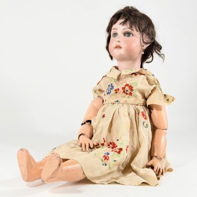 une vieille poupée assise par terre, sur un fond blanc