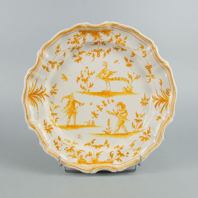 une assiette jaune et blanche ornée d'un motif représentant des personnes