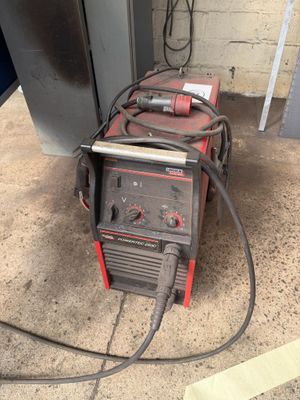 an image of a welding machine sitting on the ground next to a refrigerator
