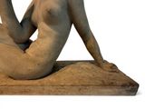a statue of a nude woman sitting on a rock