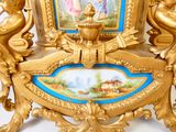 une horloge dorée ornée d'une image, posée sur une table