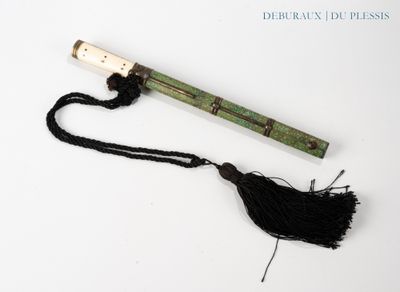 une pipe en bois ornée d'un pompon, posée sur une surface blanche