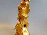 a gold figurine of a woman sitting on top of a shoe