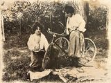 deux femmes debout à côté d'un vélo dans l'herbe