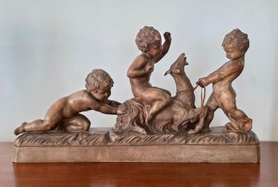 une statue représentant trois enfants jouant avec un chien sur une table