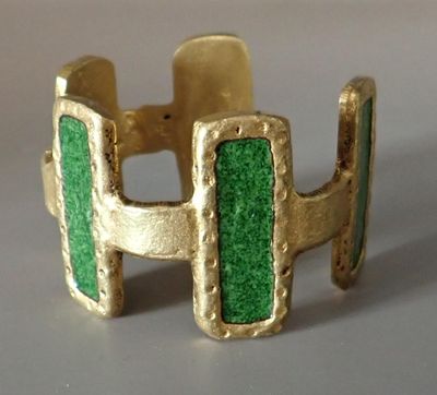 Gros plan sur une bague en or ornée d'une pierre verte