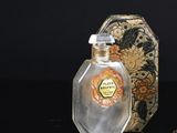 a bottle of perfume next to a gold ring on a table