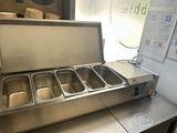 stainless steel counter top with four pans of food in a commercial kitchen